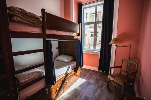 Zimmer mit Etagenbetten, einem Fenster und einem Stuhl in der Unterkunft Home Lisbon Hostel in Lissabon
