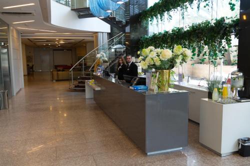 zwei Personen sitzen an einer Theke in einer Lobby in der Unterkunft Benjamin Business Hotel in Herzlia