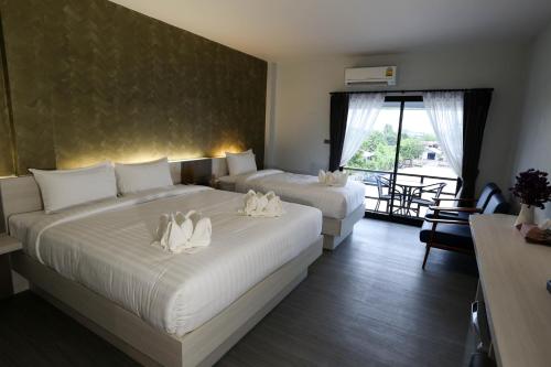 a hotel room with two beds and a balcony at Socool Grand Hotel in Nang Rong