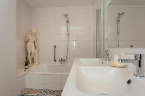 a white bathroom with a sink and a bath tub at Het Vakwerkhuis in Valkenburg