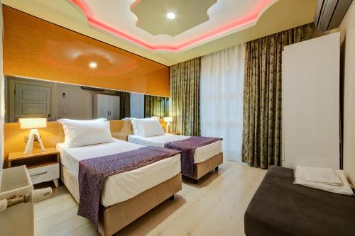 een hotelkamer met 2 bedden en een bank bij Mersin Vip House Hotel in Mersin