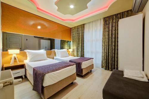 a hotel room with two beds and a couch at Mersin Vip House Hotel in Mersin