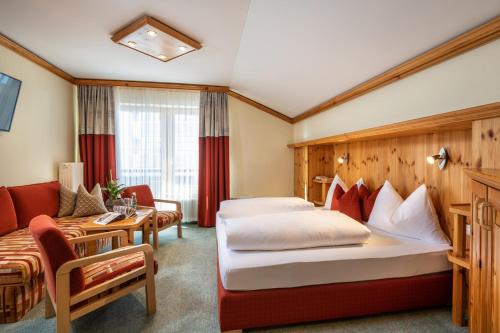 um quarto de hotel com duas camas e um sofá em Hotel Garni Haus Tyrol em Obertauern