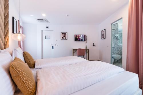 a white bedroom with two beds and a bathroom at Filitti Boutique Hotel in Bucharest