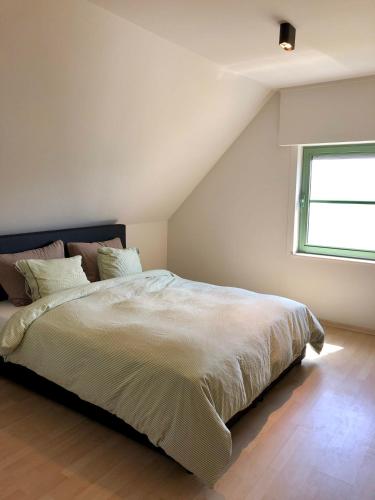 a bedroom with a large white bed with a window at Nieuwendamme 80 in Nieuwpoort