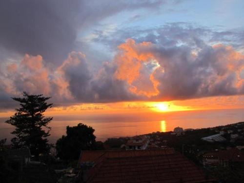 a sunset over the ocean with the sun setting at Madeira House in Calheta