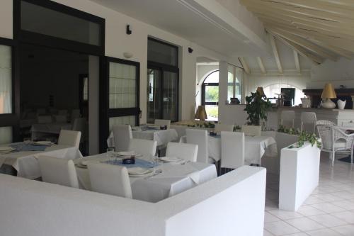 un comedor con mesas blancas y sillas blancas en Hotel La Settima Luna en Savudrija