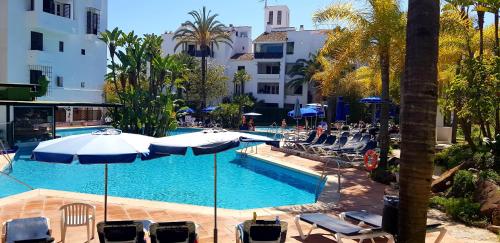 a swimming pool with chairs and umbrellas in a resort at Penthouse in Jardines De Las Golondrinas in Marbella