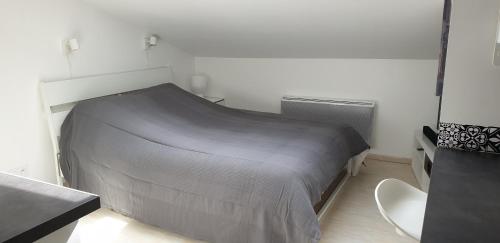 - une chambre avec un lit gris dans l'établissement joli studio calme coeur de ville, à Nancy