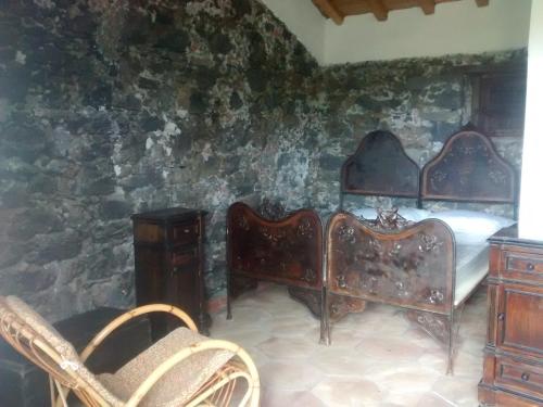 a bedroom with two beds and a stone wall at Agriturismo La Caraffara sull' Etna in Puntalazzo
