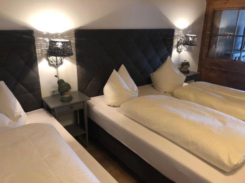 a bedroom with two beds with white sheets and two lamps at Gästehaus Weiherhof in Alpbach
