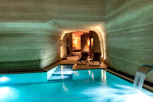 a swimming pool in a building with two chairs at Carus Cappadocia in Göreme