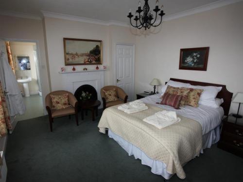 a bedroom with a bed and two chairs and a fireplace at Castle House Hotel in Canterbury