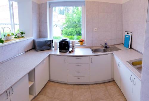 a kitchen with white counters and a sink and a window at Kőszeg Panzió in Kőszeg