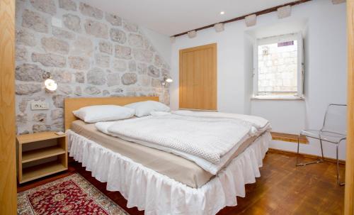 a bedroom with a large bed with a stone wall at Apartment Sorta in Dubrovnik