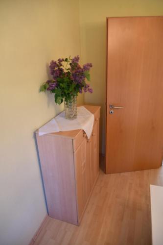 a vase of flowers sitting on top of a cabinet next to a door at Ferienwohnung Kaiser Lothar in Süpplingenburg