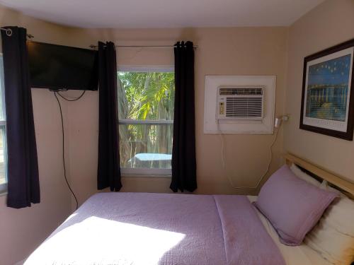 a bedroom with a bed with a television and a window at Siesta Motel in Marathon