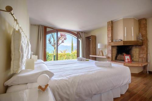 a bedroom with a large white bed and a fireplace at Maison Balù Villa in Torri del Benaco