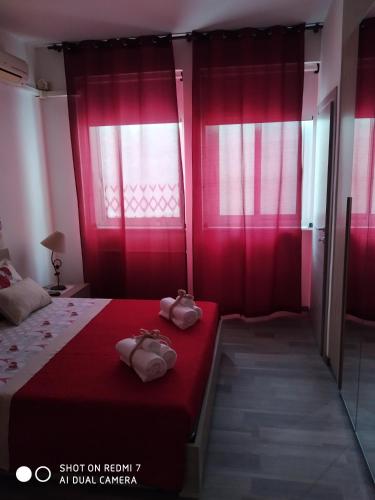 een slaapkamer met rode gordijnen en een bed met 2 schoenen bij L'Angolo XXIV Maggio in Lecce