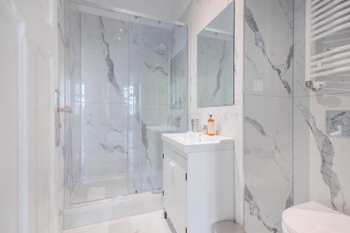 a white bathroom with a shower and a sink at Riviera Residence Apartments in Sopot