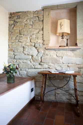 a table in front of a stone wall with a lamp at B&B Le Cannelle FIESOLE in Fiesole