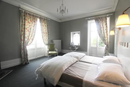 une chambre avec un grand lit et deux fenêtres dans l'établissement Domaine de Planchoury, à Saint-Michel-sur-Loire