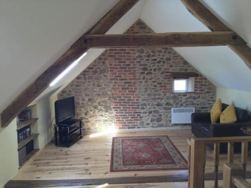 a loft conversion with a brick wall and a living room at Chez Sivade Gîte in La Crouzille