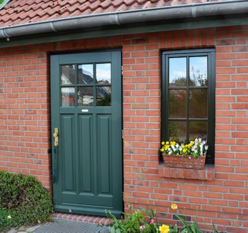 a brick house with a green door and two windows at Ferienwohnungen Meyer in Bollewick