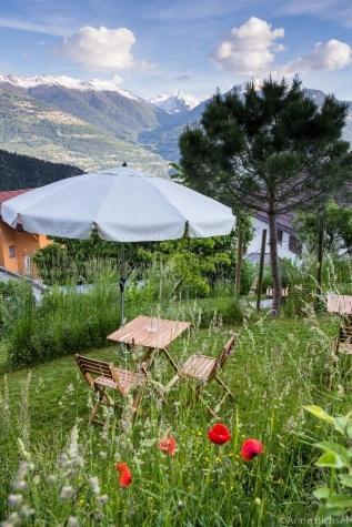 a table and chairs under an umbrella in a field of flowers at La Grande Maison in Savièse