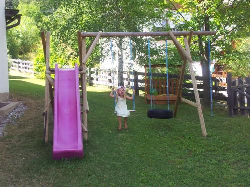 a woman standing next to a slide in a playground at Ferienhaus Viktoria in Abfaltersbach
