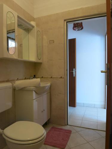 baño con aseo, lavabo y puerta en Apartments Mićo, en Rab