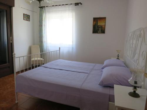 Un dormitorio con una cama con sábanas moradas y una ventana en Apartments Mićo, en Rab