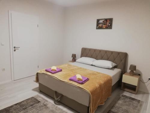 Un dormitorio con una cama con toallas moradas. en Apartman Gosto, en Mostar