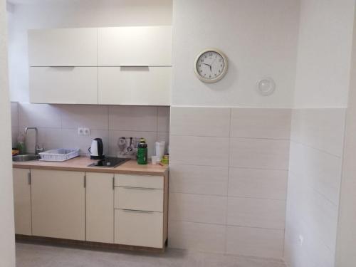 una cocina con armarios blancos y un reloj en la pared en Apartman Gosto, en Mostar