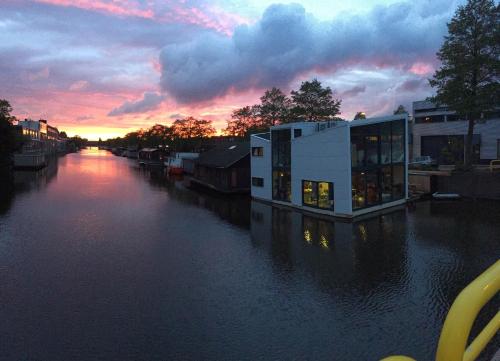 a building on a river with a sunset in the background at Reiwa in Amsterdam