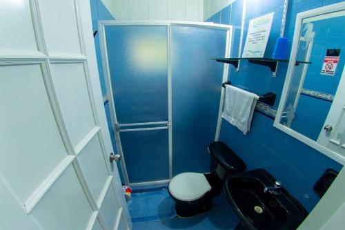 a blue bathroom with a toilet and a shower at Posada Nativa Atardecer Isleño in San Andrés