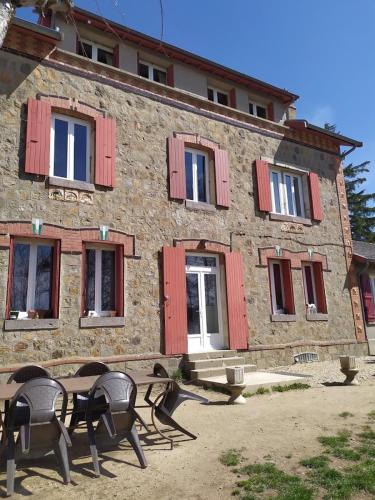 a building with chairs and a table in front of it at La Cabanette in Saint-Agrève