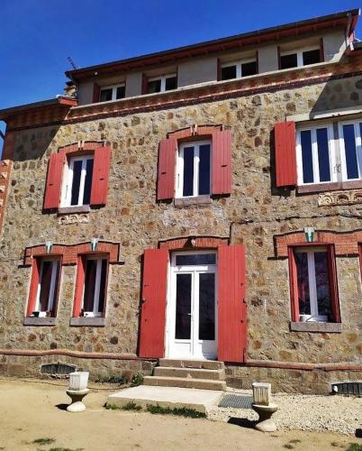 an old stone building with red shutters and a white door at La Cabanette in Saint-Agrève