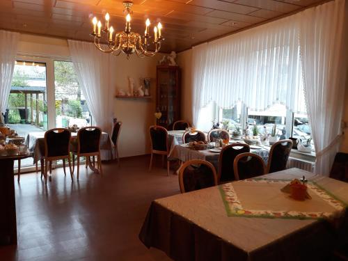 a dining room with tables and chairs and a chandelier at Pension Haus Thies in Cochem