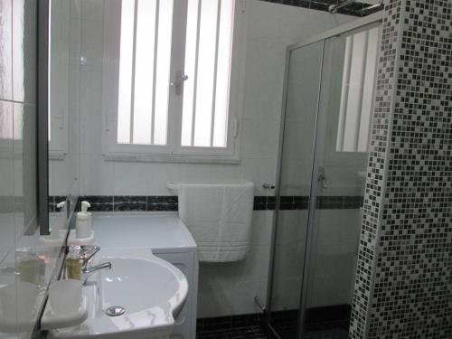 a white bathroom with a sink and a shower at Maison Gigante in San Donato di Lecce