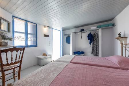 een slaapkamer met een roze bed en een stoel bij Emmantina in Mesariá