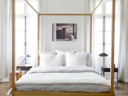 a white bedroom with a canopy bed with white pillows at Une Suite A Vannes in Vannes