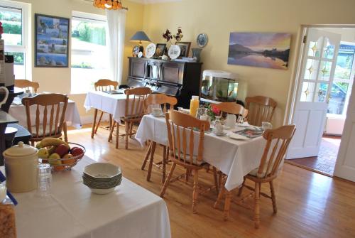 a dining room with tables and chairs and a kitchen at Cúl Draíochta B&B in Cahersiveen