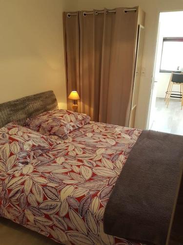 une chambre avec un grand lit avec un couvre-lit fleuri dans l'établissement Appartement Aix (1 à 2 personnes), à Châtelaillon-Plage