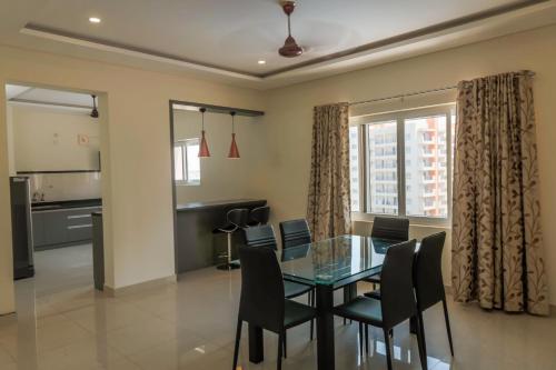 Cloud9Homes Serviced Apartments في حيدر أباد: غرفة طعام مع طاولة وكراسي زجاجية