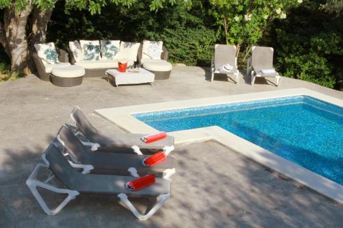 a group of lounge chairs next to a swimming pool at Masia Can Magan Lux, Ideal Grupos 20pax in Palafolls