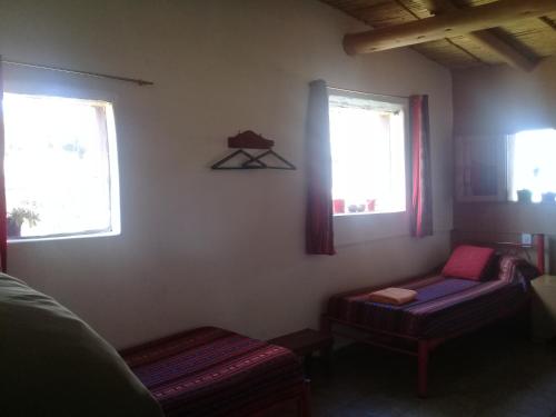 a room with two windows and a couch and a chair at Cabaña El Cardón,casita en el campo quebradeño in Humahuaca