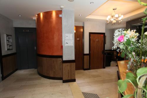 a hallway with wooden doors and flowers in a lobby at Hôtel Alane in Paris