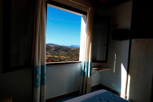 a window in a bedroom with a view of a mountain at Agriturismo Irghitula in Posada