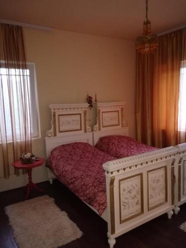 a bedroom with a white bed with a red bedspread at Vila Kraljica in Vrdnik